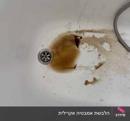אמבטיה מוכתמת ובלויה עם מים עכורים ליד הניקוז לפני חידוש